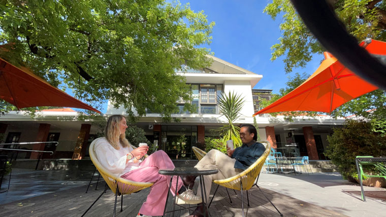 two people sit outside drinking coffee