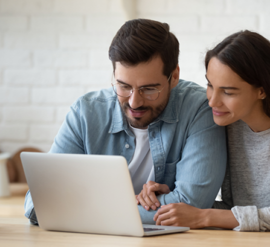 Couple looking at their laptop from a home environment.