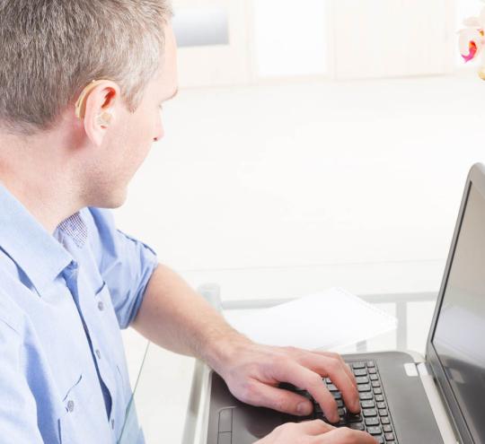 Deaf man using typing on a laptop.