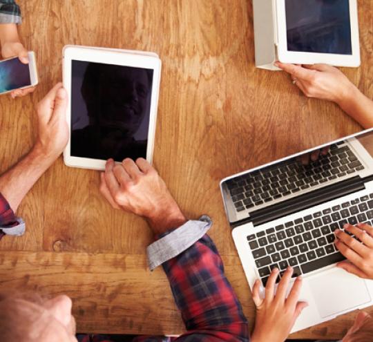 Family around a table on various electronic devices