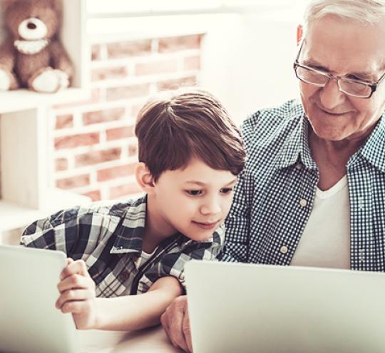 Child and grandfather looking at computer tablets