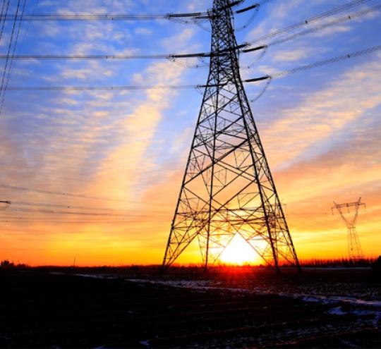 Power lines in a field at sunset.