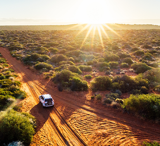 Four wheel drive driving in country road at sunset.