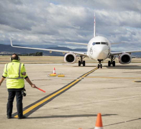 Ground crew guides airplane as it taxis on runway 