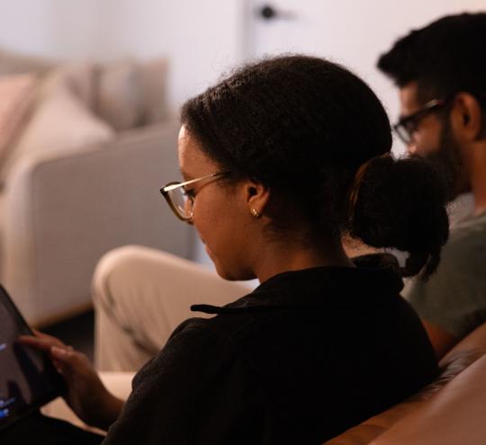 A couple sitting on the couch using a tablet.