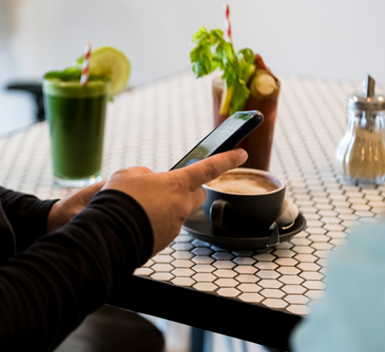 Person at a cafe shop looking at their mobile phone