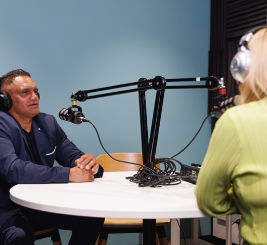 Man and woman wearing headphones and talking into microphones