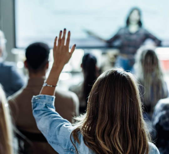 Back view image of a woman raising her hand in a presentation