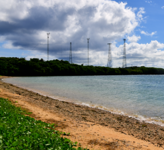 Tropical beach with telecommunications towers in the distance.