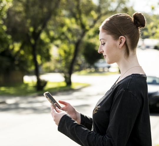 A woman standing on the street, looking at her phone