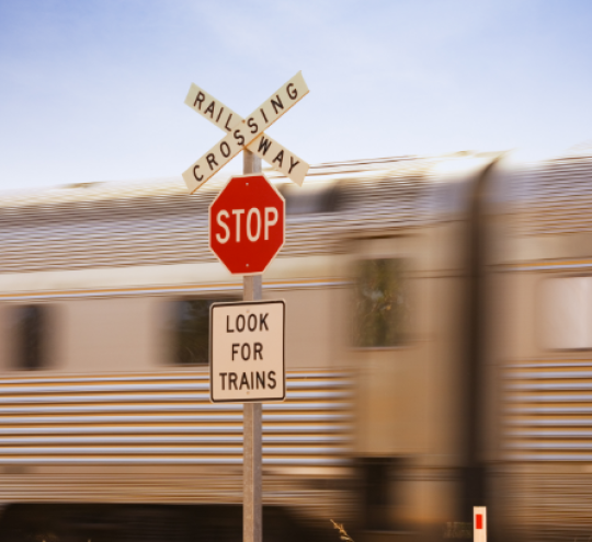 Railway Crossing STOP sign and a train passing behind the sign.