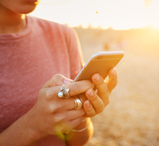 Women texting on her phone on a beach at sunset