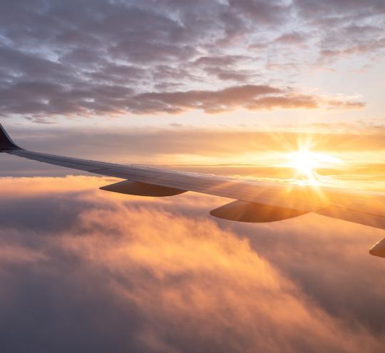 Airplane wing with clouds and sunset