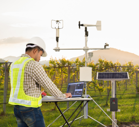 Agronomist using tablet computer to collect data with meteorological instruments in grape agricultural field.