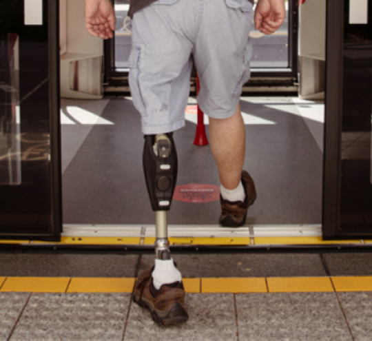 Man with prosthetic leg boarding light rail carriage.