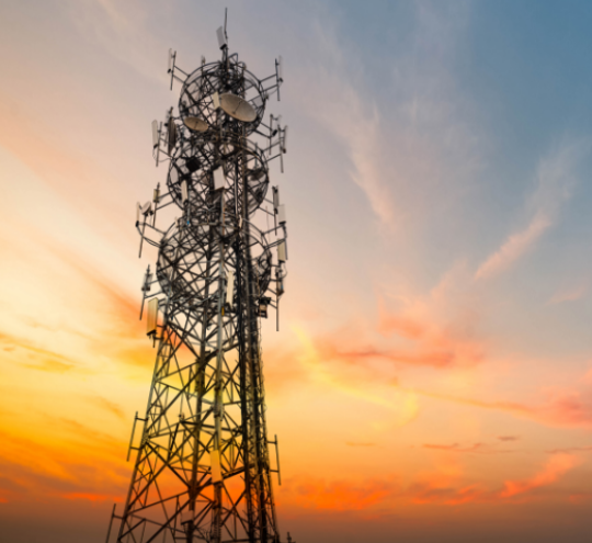 Image of a radio tower with the sun setting behind it. 