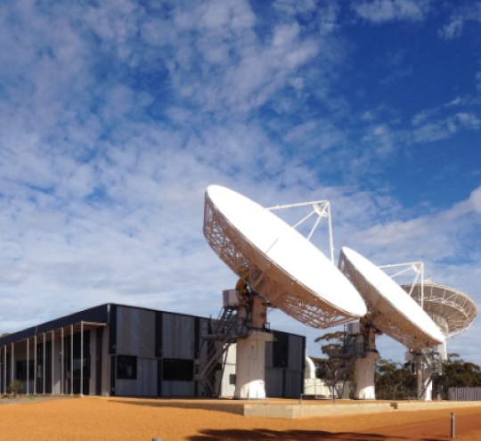 Image of satellite ground station with blue sky and clouds in the background.