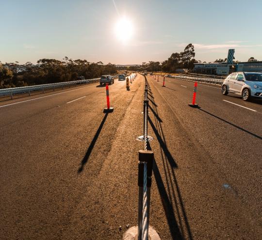 Newly installed wire rope safety barrier in centre of road.