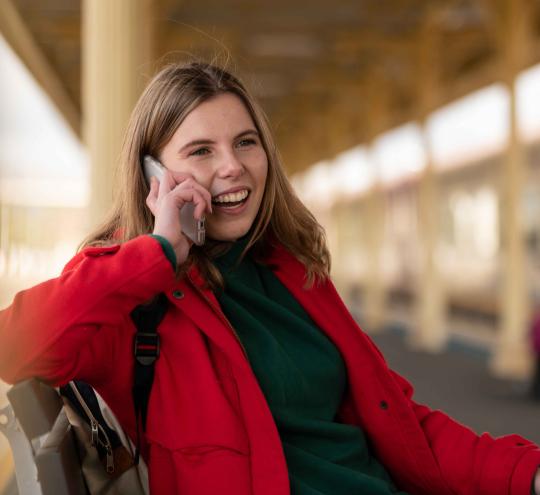 Woman at train station talking on mobile.