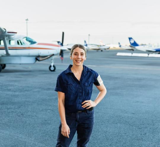 Woman standing in front of planes on a tarmac.