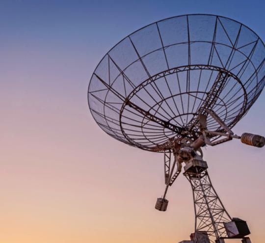 Satellite dish pointing towards the sky at sunset.