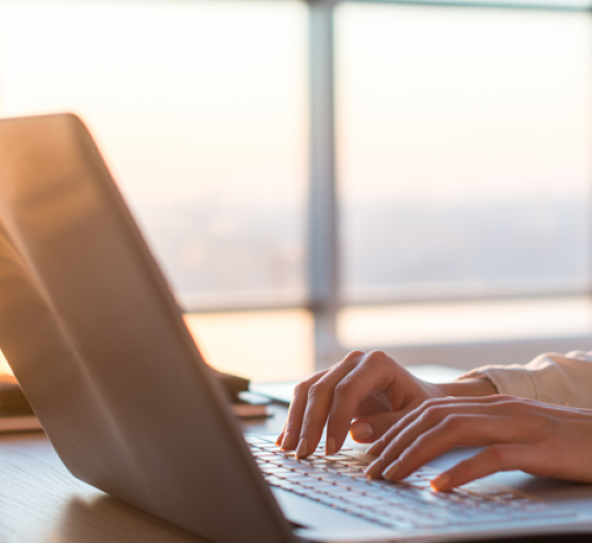 Woman using a laptop on an office desk.