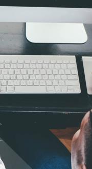 Male sitting at desk and typing on keyboard.