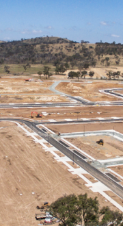 Image of land cleared ready for new buildings. Streets are paved and there are a couple of larger trees.