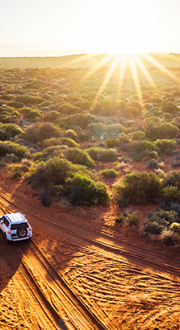 Four wheel drive driving in country road at sunset.