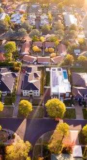 Birds eye view of a community, featuring roads, houses and trees.