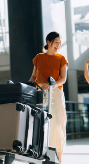 Mother and daughter walking through the airport terminal with their suitcases.