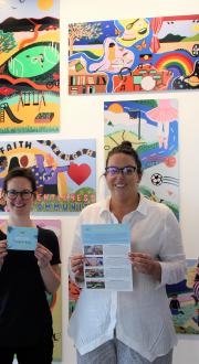 An image of three people involved with the Central Grampians Local Learning and Employment Network Inc’s ‘Ararat Schools Resilient Art Project’, to build positive educational outcomes and increase the resilience of young people in the community by delivering an art-based wellbeing program. The three people are smiling and standing in front of colourful artwork hung on a wall. Image credit: FRRR