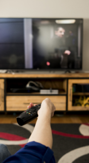 A mother and child sitting on a couch holding a remote up to the TV.