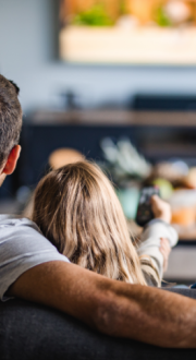 Family watching a screen on the wall in their home. Child using a remote.