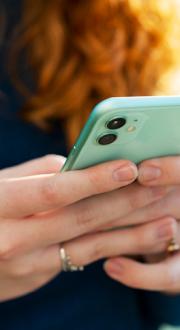 Hands using a green mobile phone device.