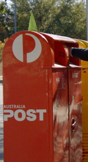 person posting letter at an Australia Post mailbox