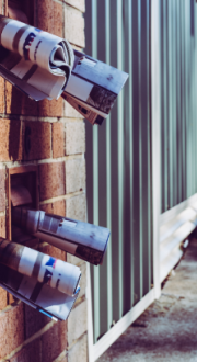 Apartment block mail boxes with rolled up newspapers sticking out of them.