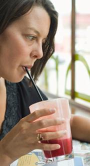 Woman drinking beverage and reading newspaper in a café.