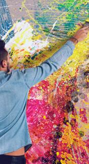 Man paints a big and colourful light bulb on a wall.