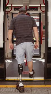 Man with prosthetic leg boards light rail carriage.