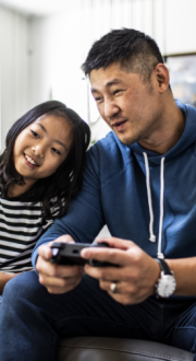 Father And Daughter Playing Video Games At Home