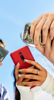 Three people holding mobile phone in their hands.