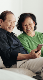 Two people sitting on a couch looking at a mobile phone 