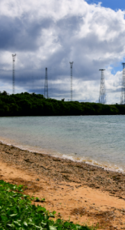 Tropical beach with telecommunications towers in the distance.