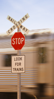 Railway Crossing STOP sign and a train passing behind the sign.