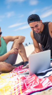 Three young friends looking at their laptop on the beach 