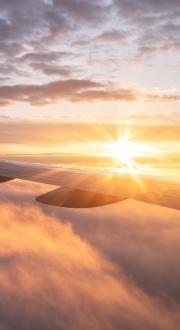 Airplane wing with clouds and sunset