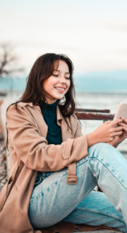 Women sitting on the edge of a pier looking at her mobile phone