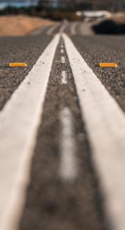 White double lines painted in the middle of a black road. 