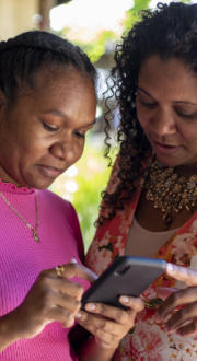 Two First Nations Woman looking at a smart phone.